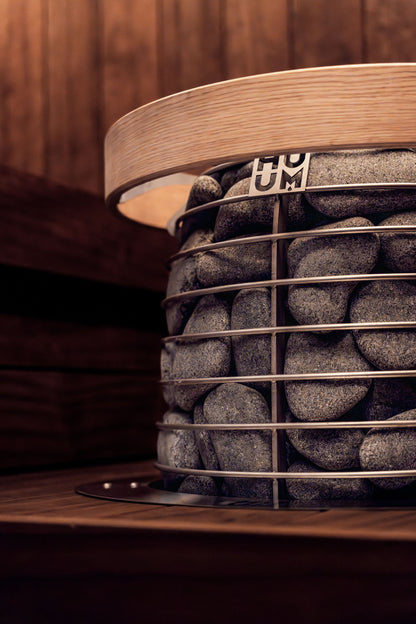 A sauna heater stacked with stones in warm low light, evoking the heat side of the spa