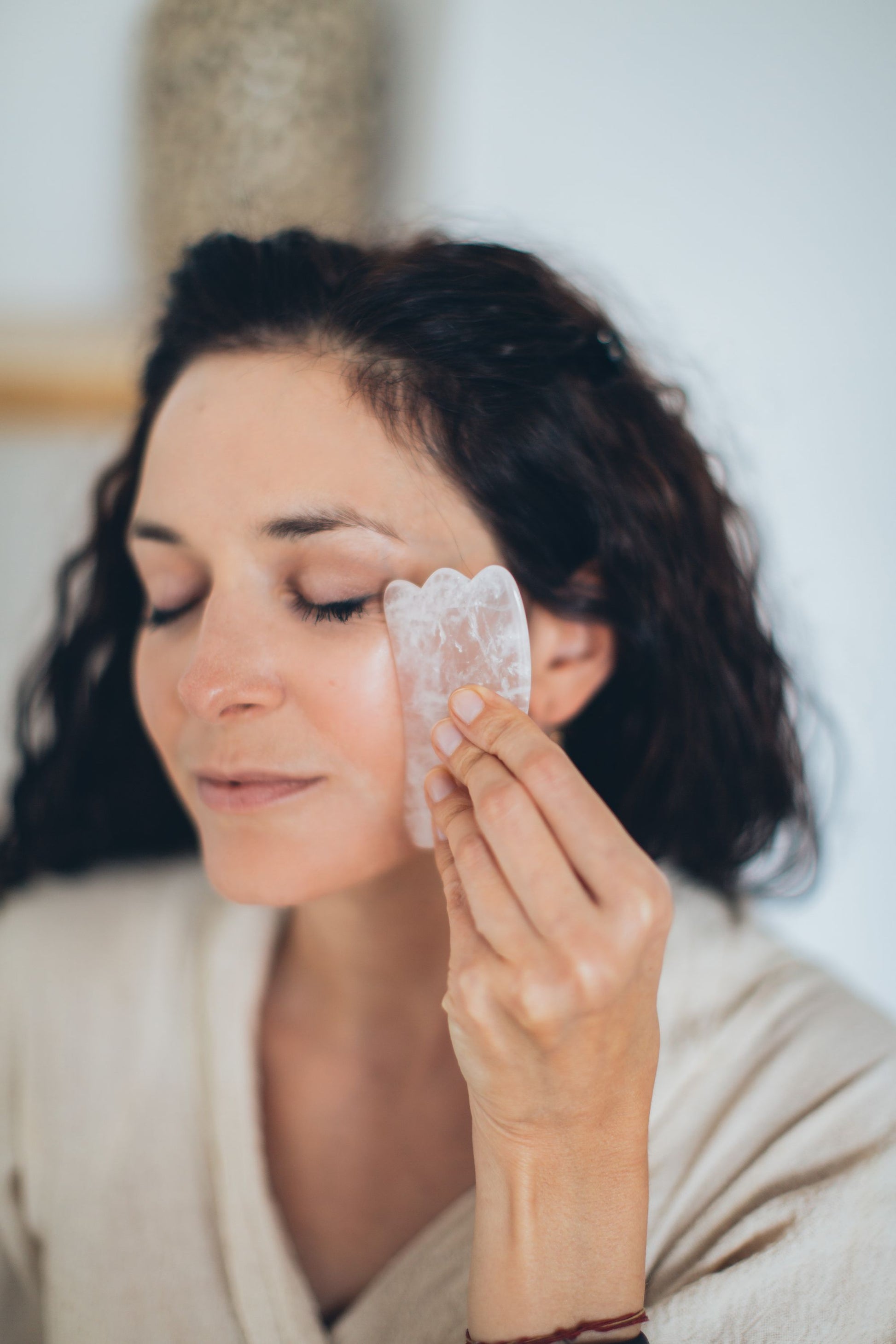 A gua sha stone smoothed across the cheek during a facial.
