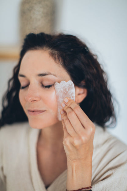 A gua sha stone smoothed across the cheek during a facial.
