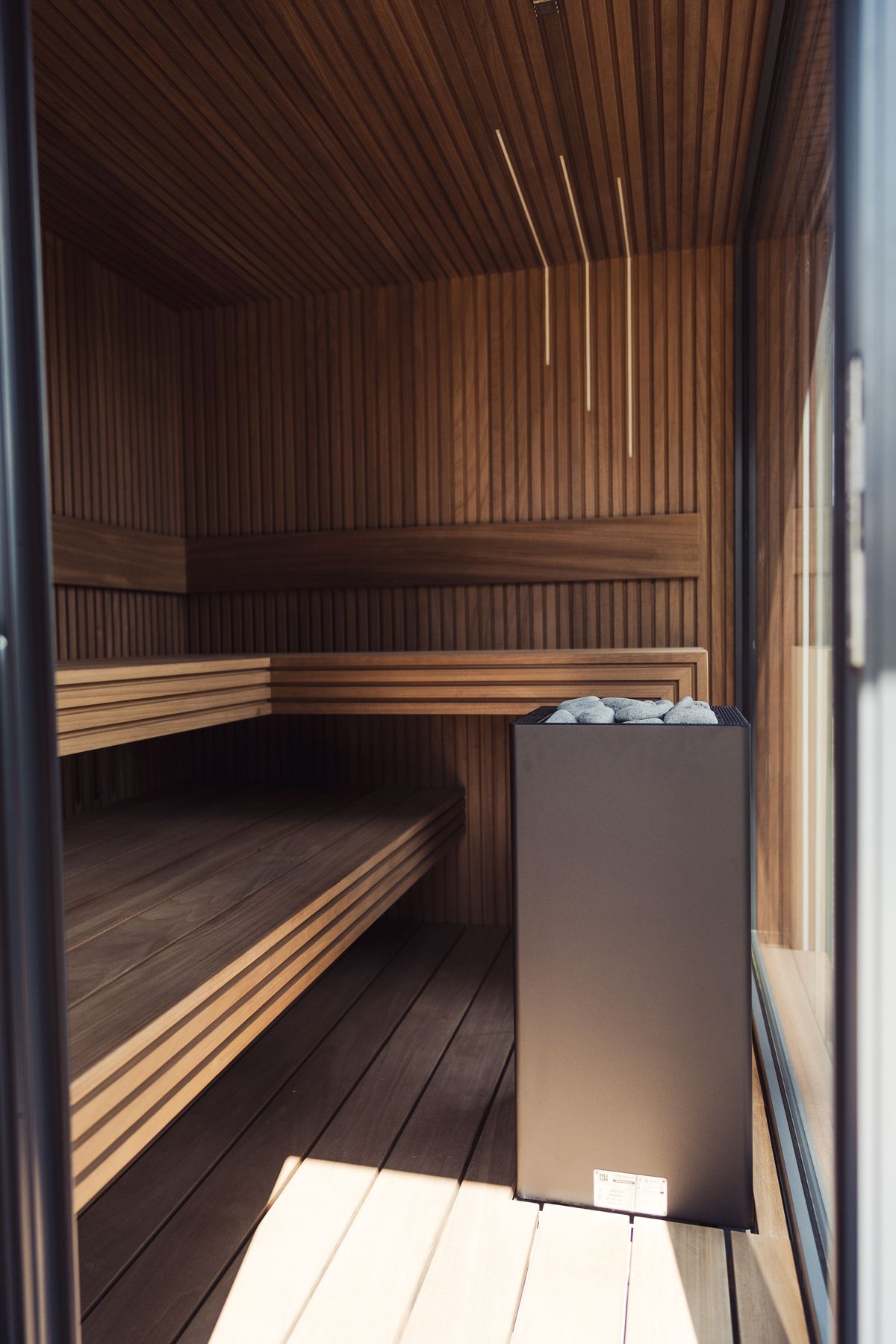 Warm wooden sauna benches in low light, evoking the heat side of a contrast therapy hydrotherapy circuit
