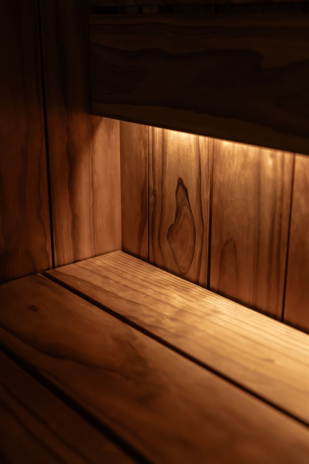 Warm light catching the grain of a wooden sauna bench