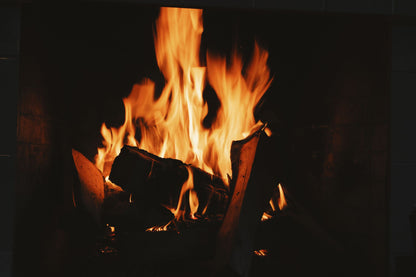 A log fire burning low in a dark hearth