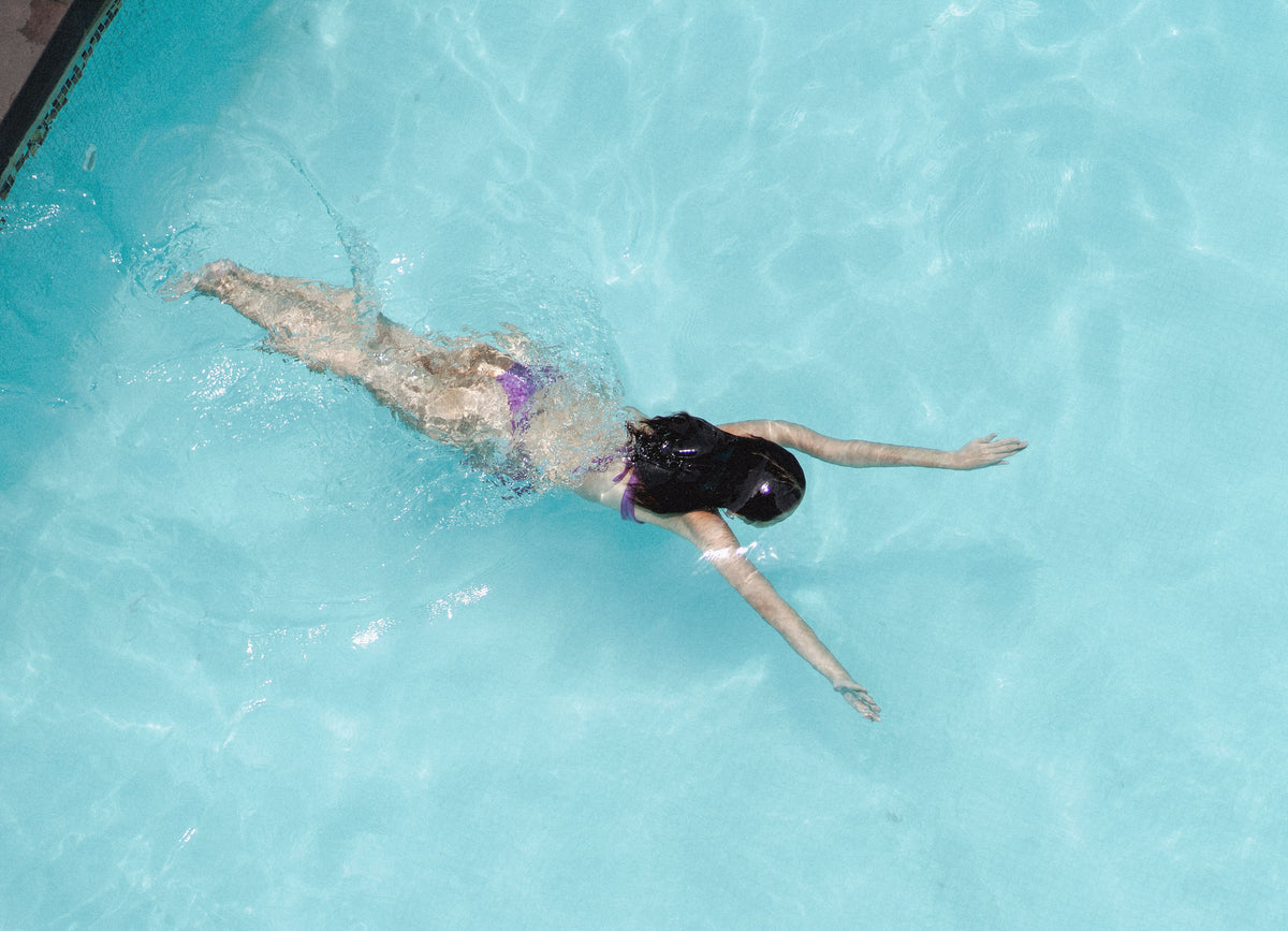 A swimmer floating on her back in bright still water, The House Spa at Dormy House, Broadway