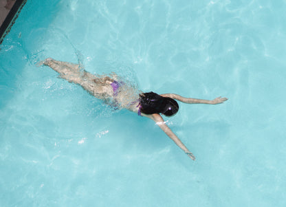 A swimmer floating on her back in bright still water, The House Spa at Dormy House, Broadway