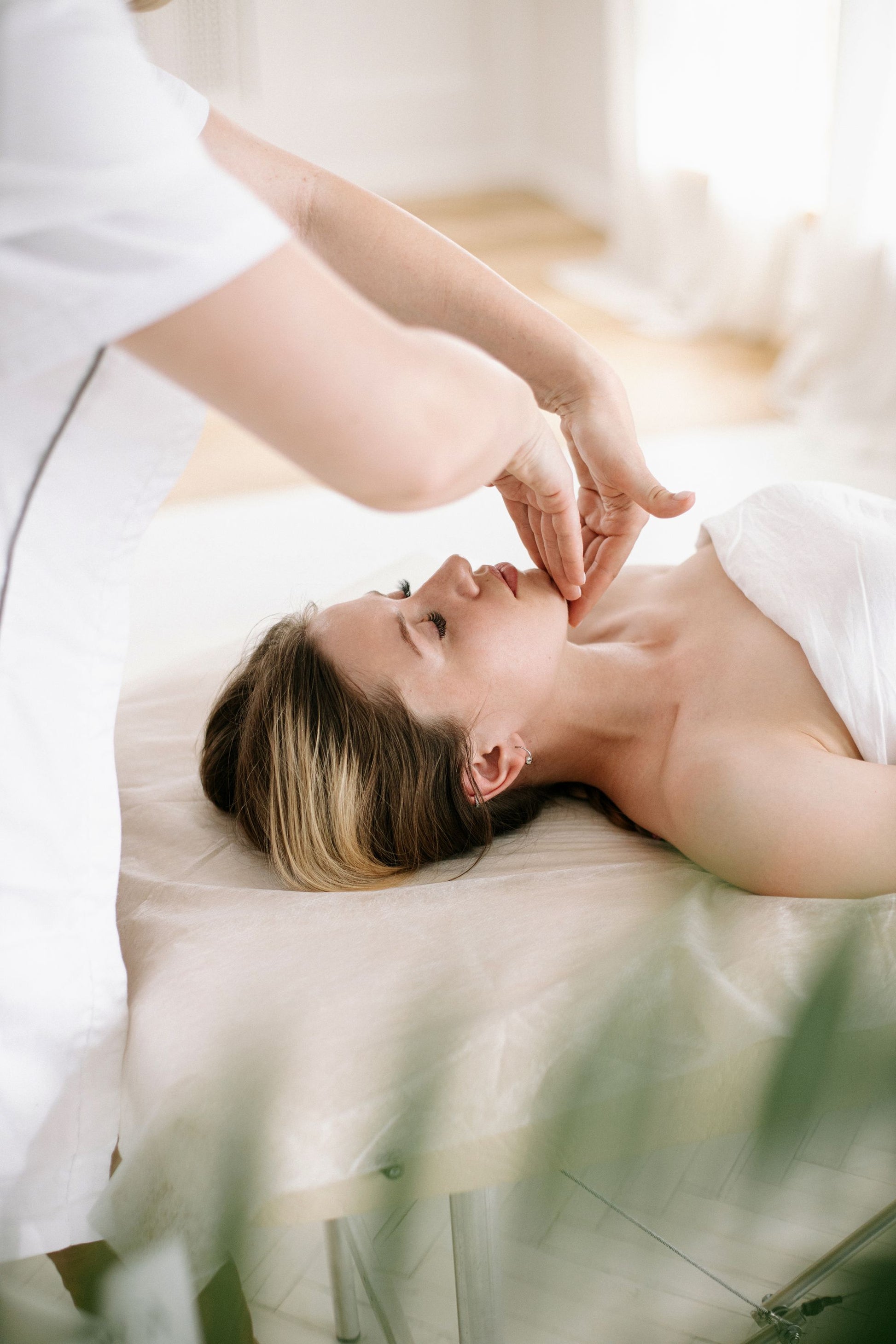 A therapist working across the temples and brow in a treatment room full of daylight