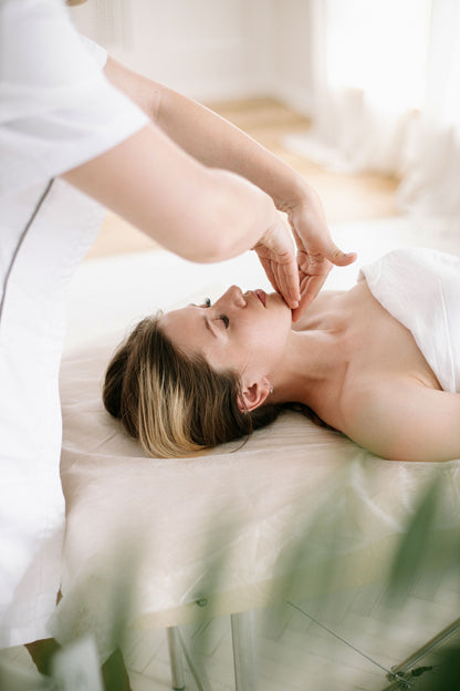 A therapist working across the temples and brow in a treatment room full of daylight