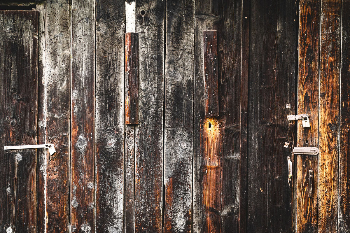 Close-up of a dark weathered wooden door with iron hardware