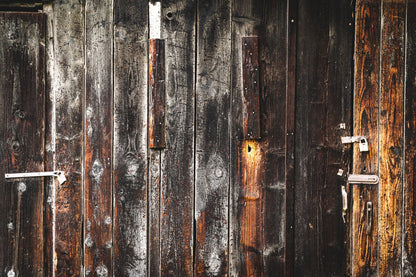 Close-up of a dark weathered wooden door with iron hardware