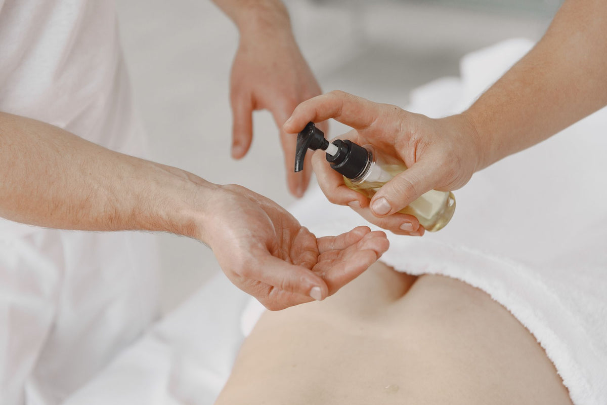 A therapist pouring massage oil into a hand before a treatment