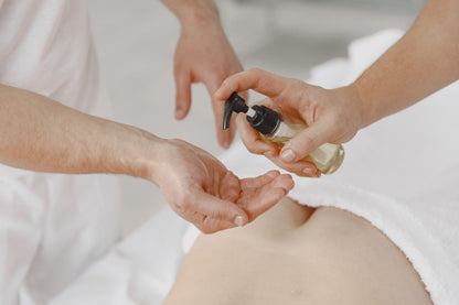 A therapist pouring massage oil into a hand before a treatment