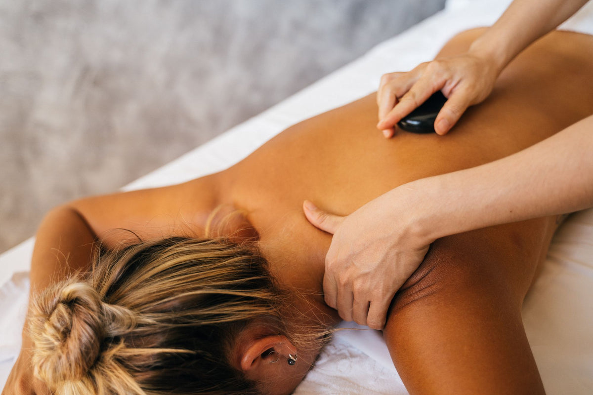 A warm stone rests against a guest shoulder during a massage.