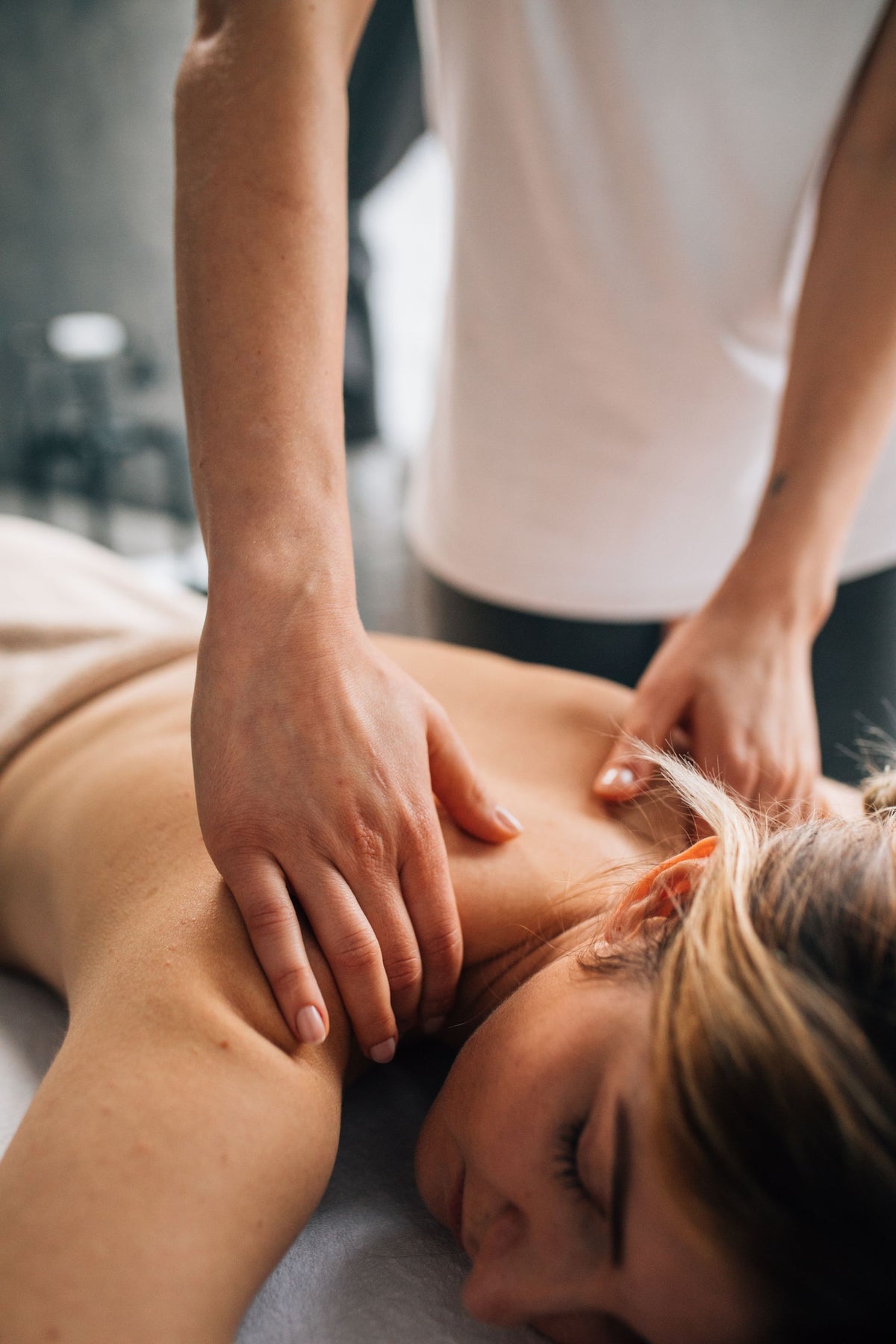 A massage therapist's hands working on a client's shoulder indoors