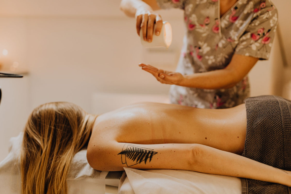 A therapist pours warm oil into her palm before a back massage.