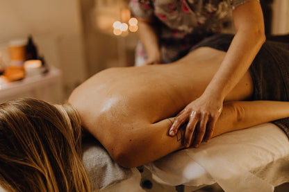 A therapist giving a back massage in a warm lit treatment room