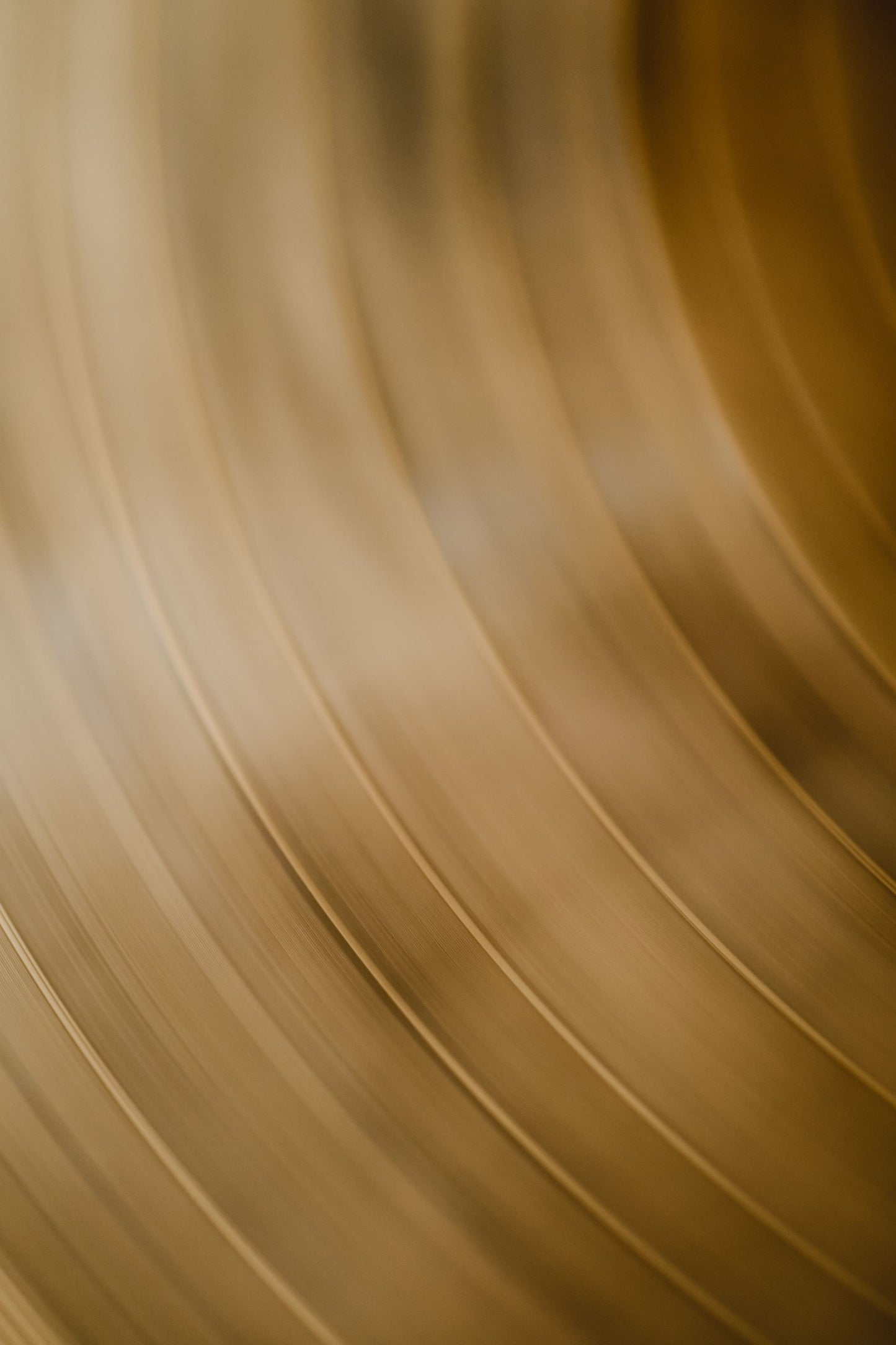 Warm brass curving away in soft focus, echoing the bronze core at Lanserhof at The Arts Club
