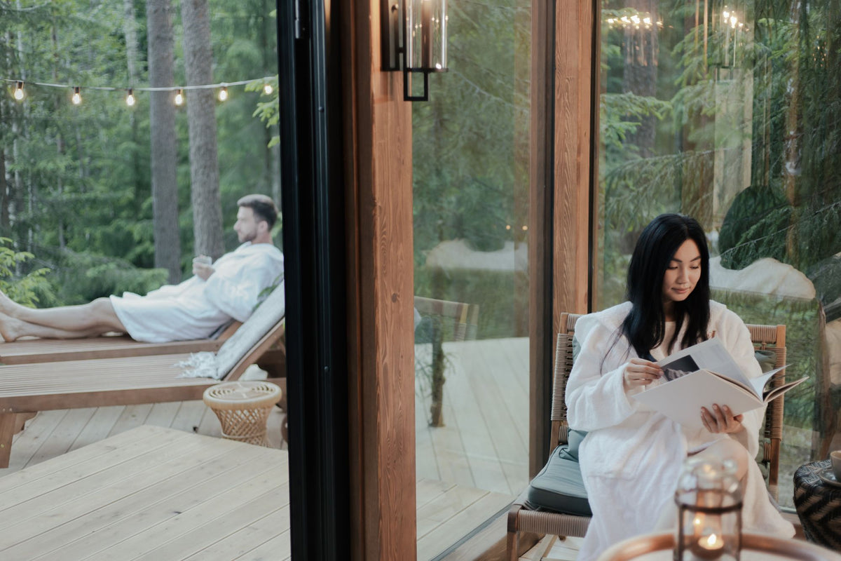 Two guests in white robes relaxing on a woodland deck in the evening light