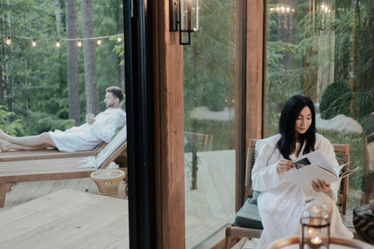 Two guests in white robes relaxing on a woodland deck in the evening light