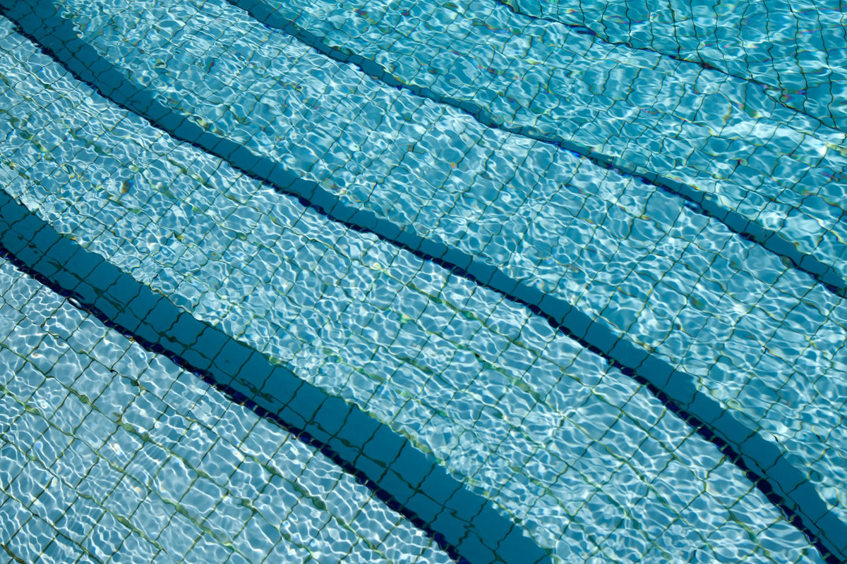 Sunlit ripples over blue tiled swimming pool water
