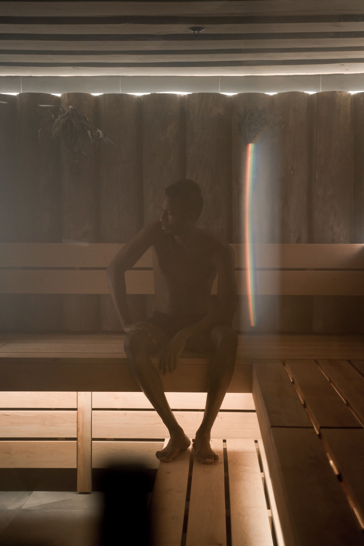 A figure silhouetted in the warm glow of a wood panelled sauna, evoking the spa's private saunas and steam rooms