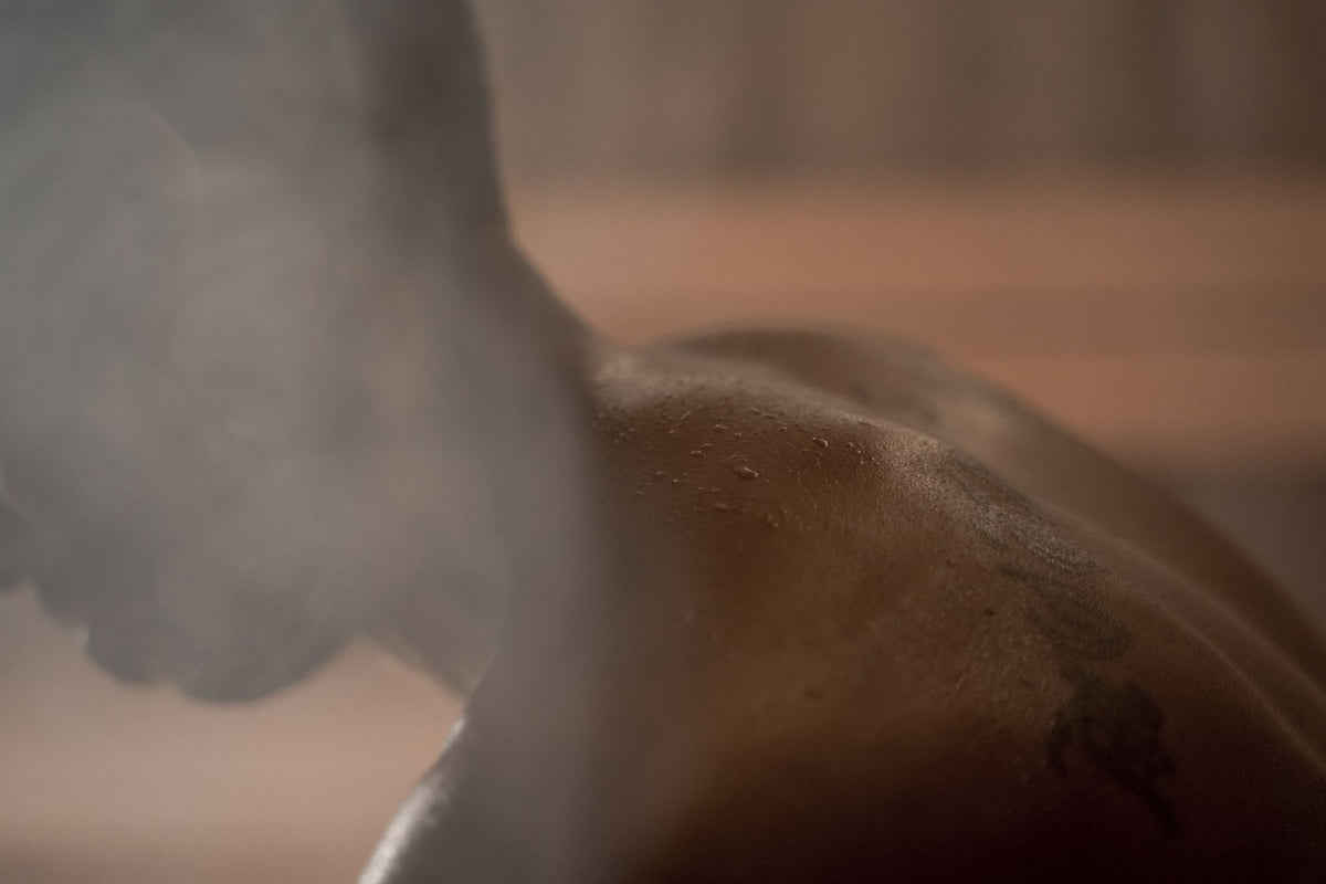 Warm steam drifting over a bare shoulder in soft amber light, evoking the sauna and hammam at the Dior Spa in Paris