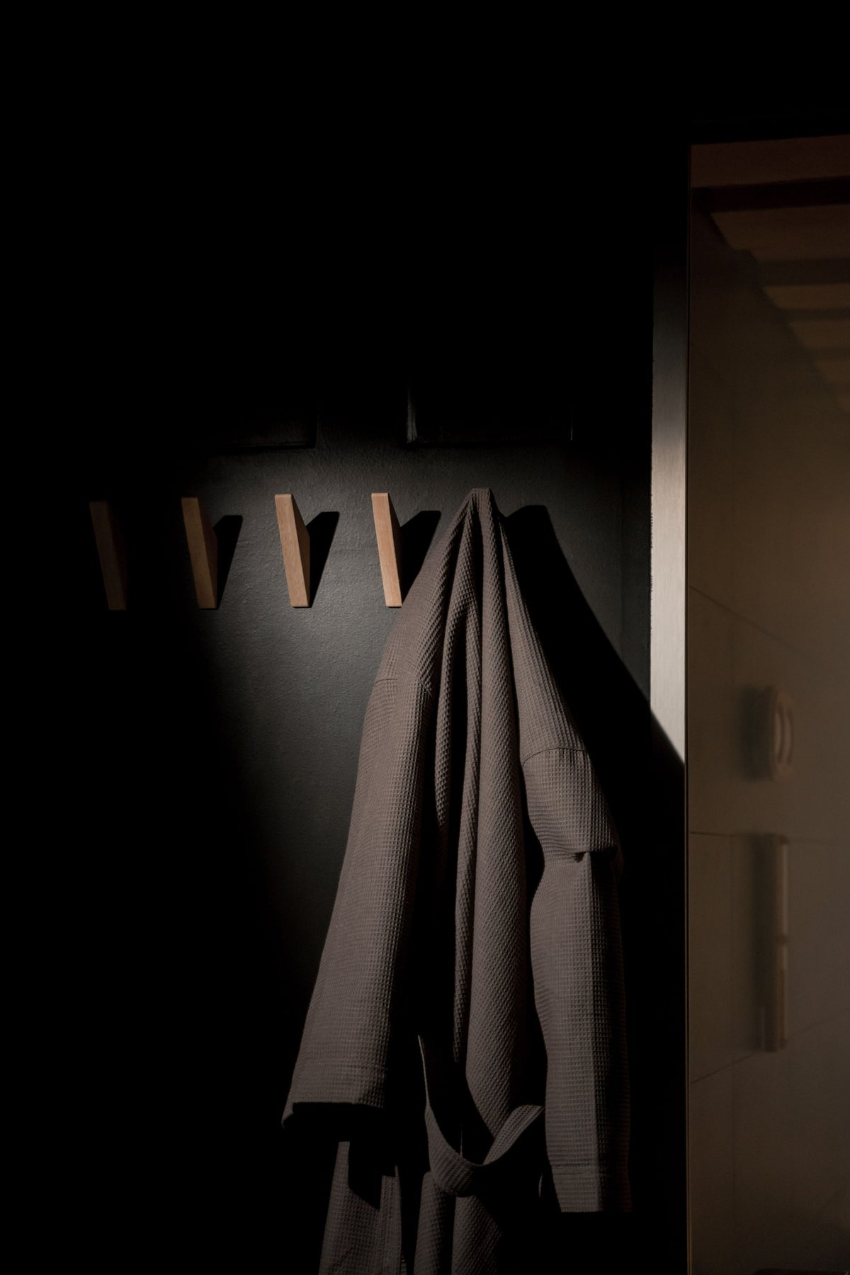 A folded bathrobe hangs alone in warm low light at Pale Hall's recovery club, the moment before a session begins