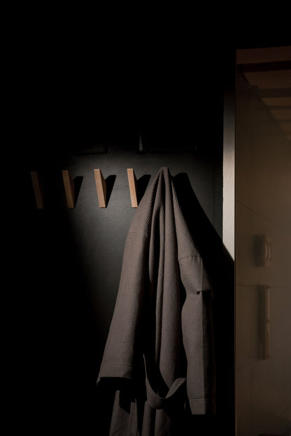 A folded bathrobe hangs alone in warm low light at Pale Hall's recovery club, the moment before a session begins