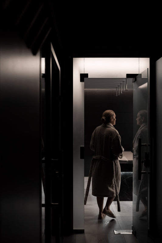 A figure in a spa robe passing into a softly lit thermal suite, The Lanesborough Club & Spa