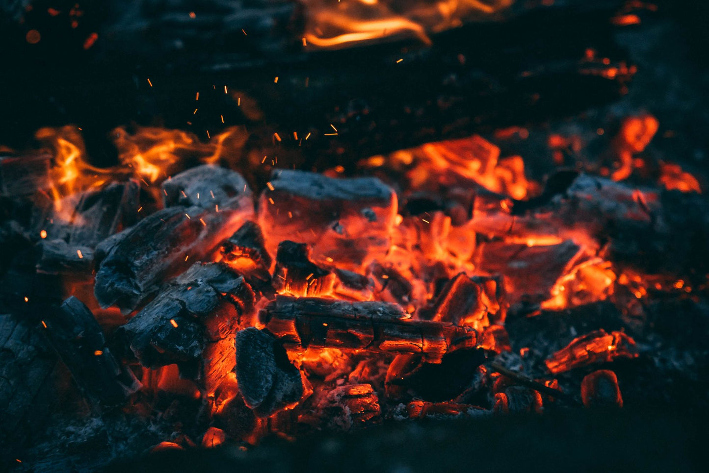 Embers glowing orange in a dying wood fire.