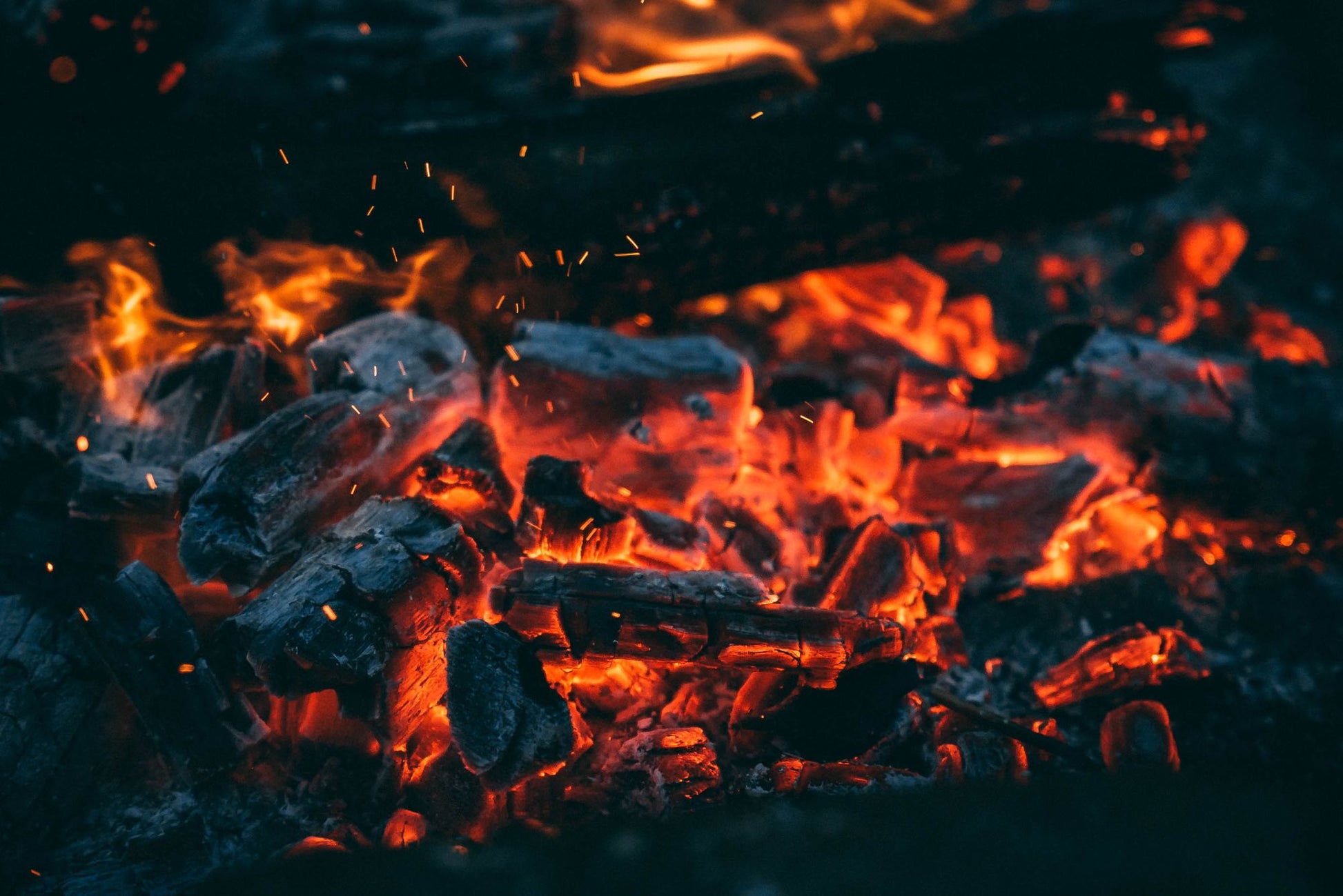 Embers glowing orange in a dying wood fire.