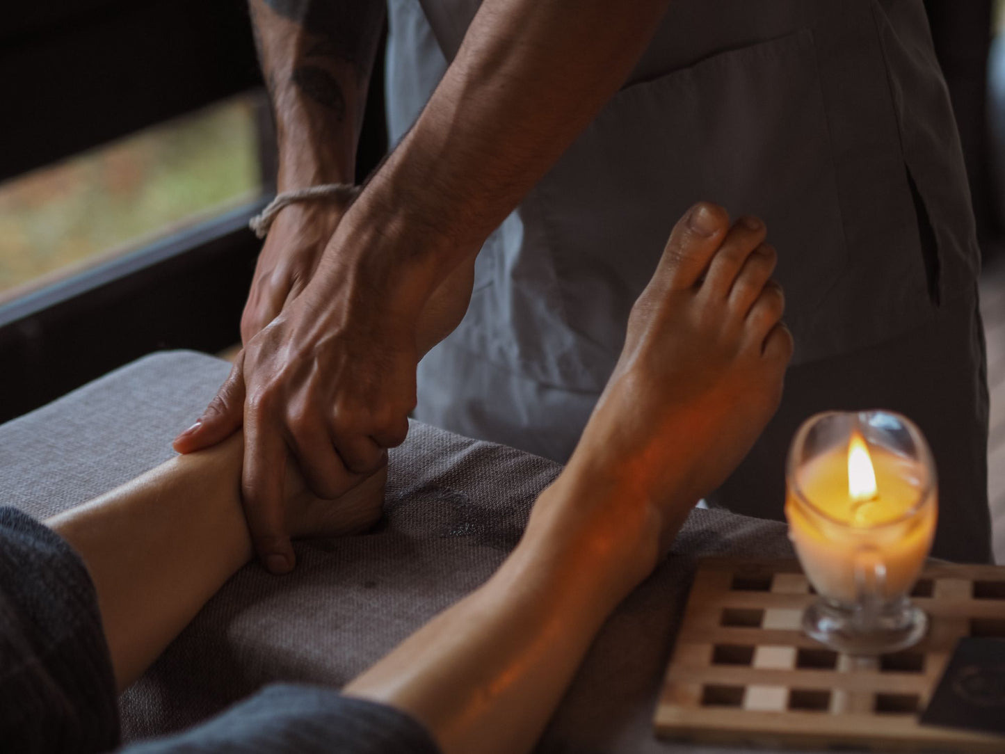 Hands giving a warm foot massage by candlelight at a Bath spa