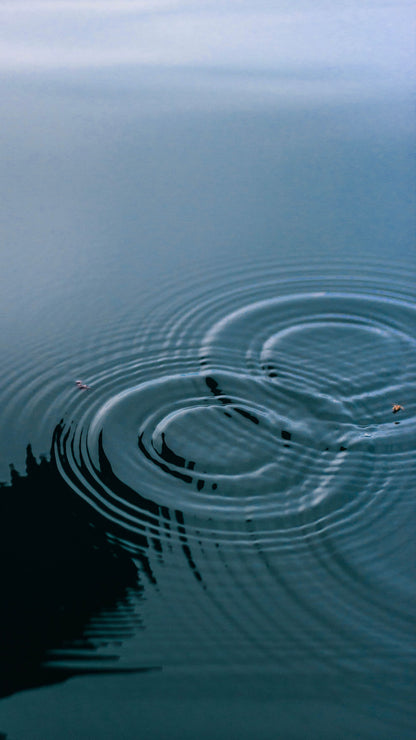 Concentric ripples spreading across cool teal water, evoking an indoor pool filled from a well on a Castilla y León wine estate