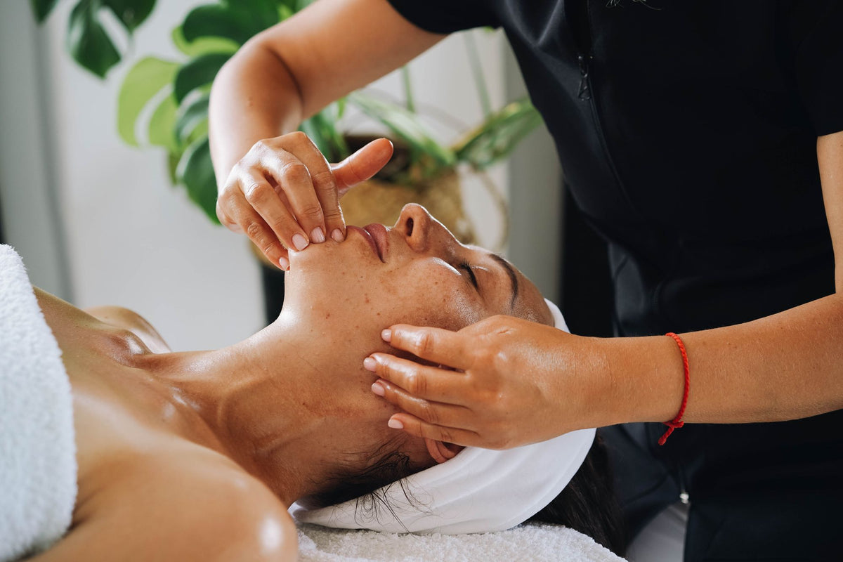 A therapist works a facial treatment into a guest's skin with slow, careful hands.
