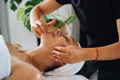 A therapist works a facial treatment into a guest's skin with slow, careful hands.